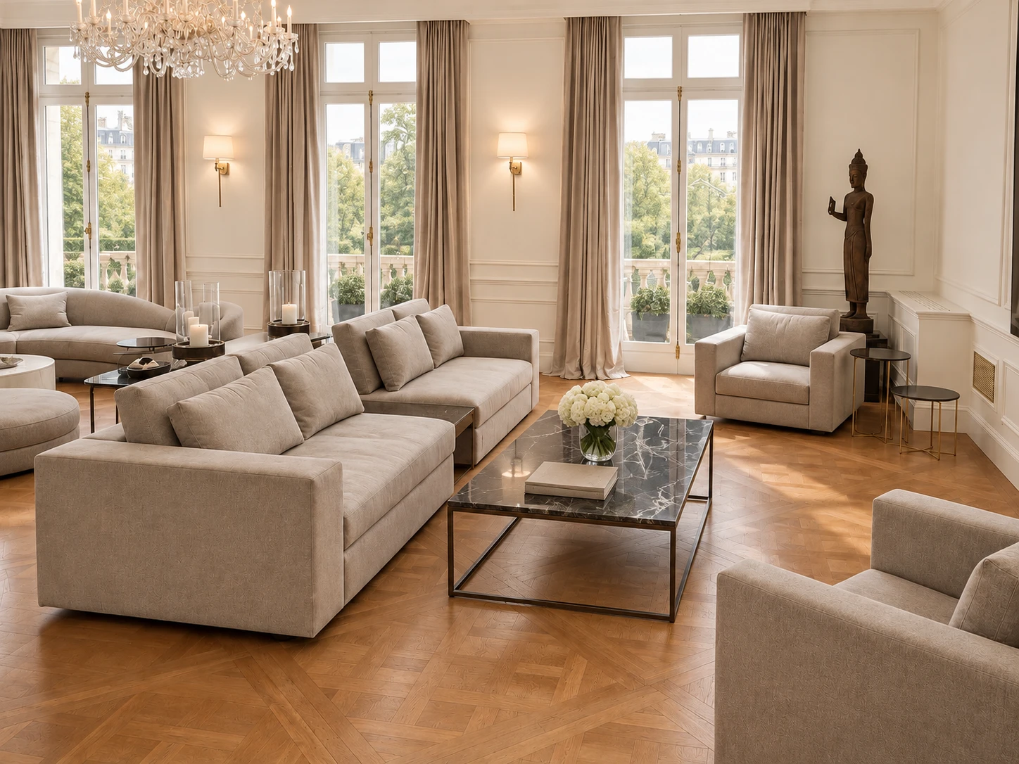 A tall drawing room with French windows: two deep sofas and armchairs in soft taupe fabric around a marble coffee table