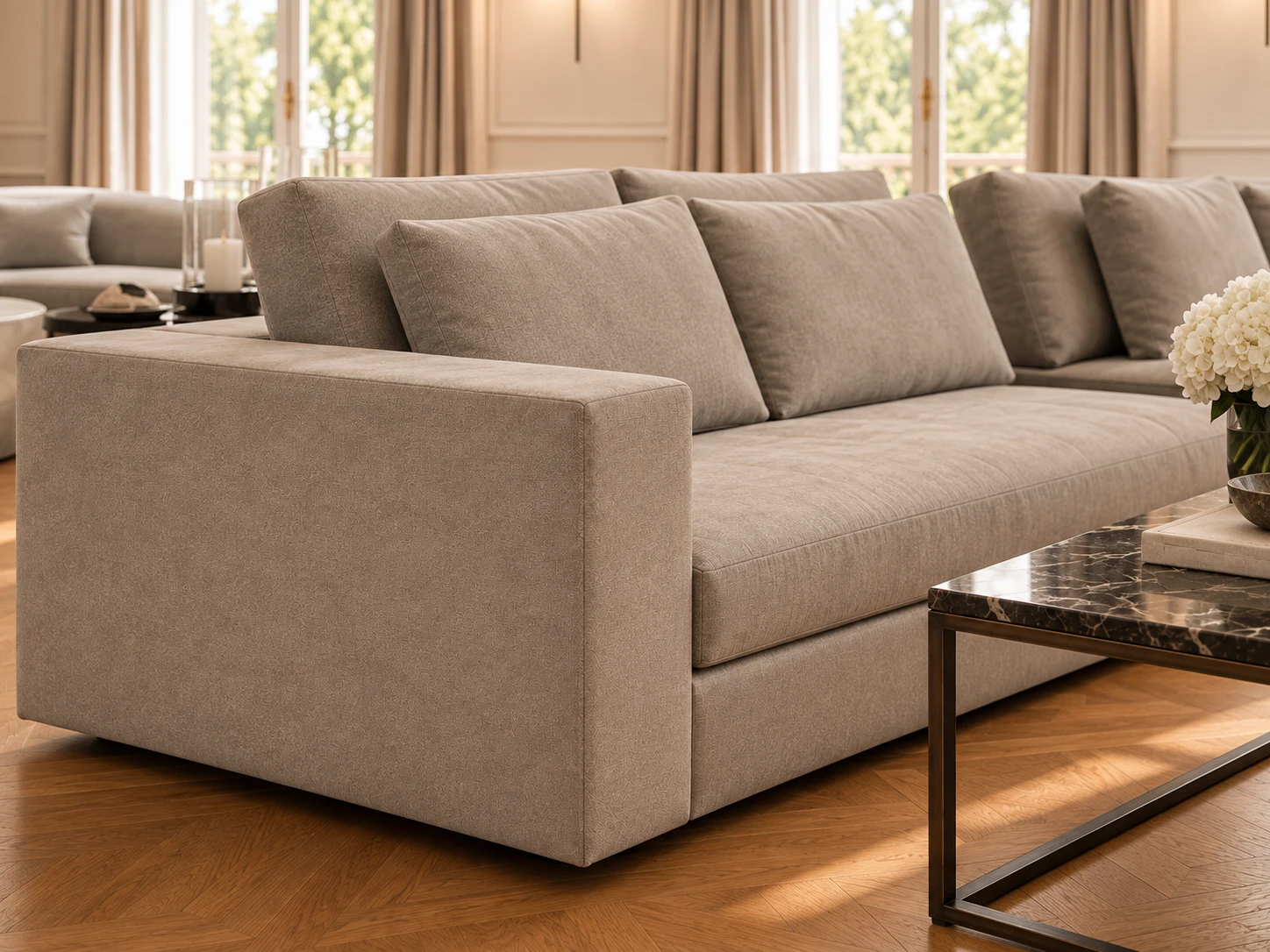 Detail of a sofa: a broad square arm and deep seat in finely patterned taupe fabric