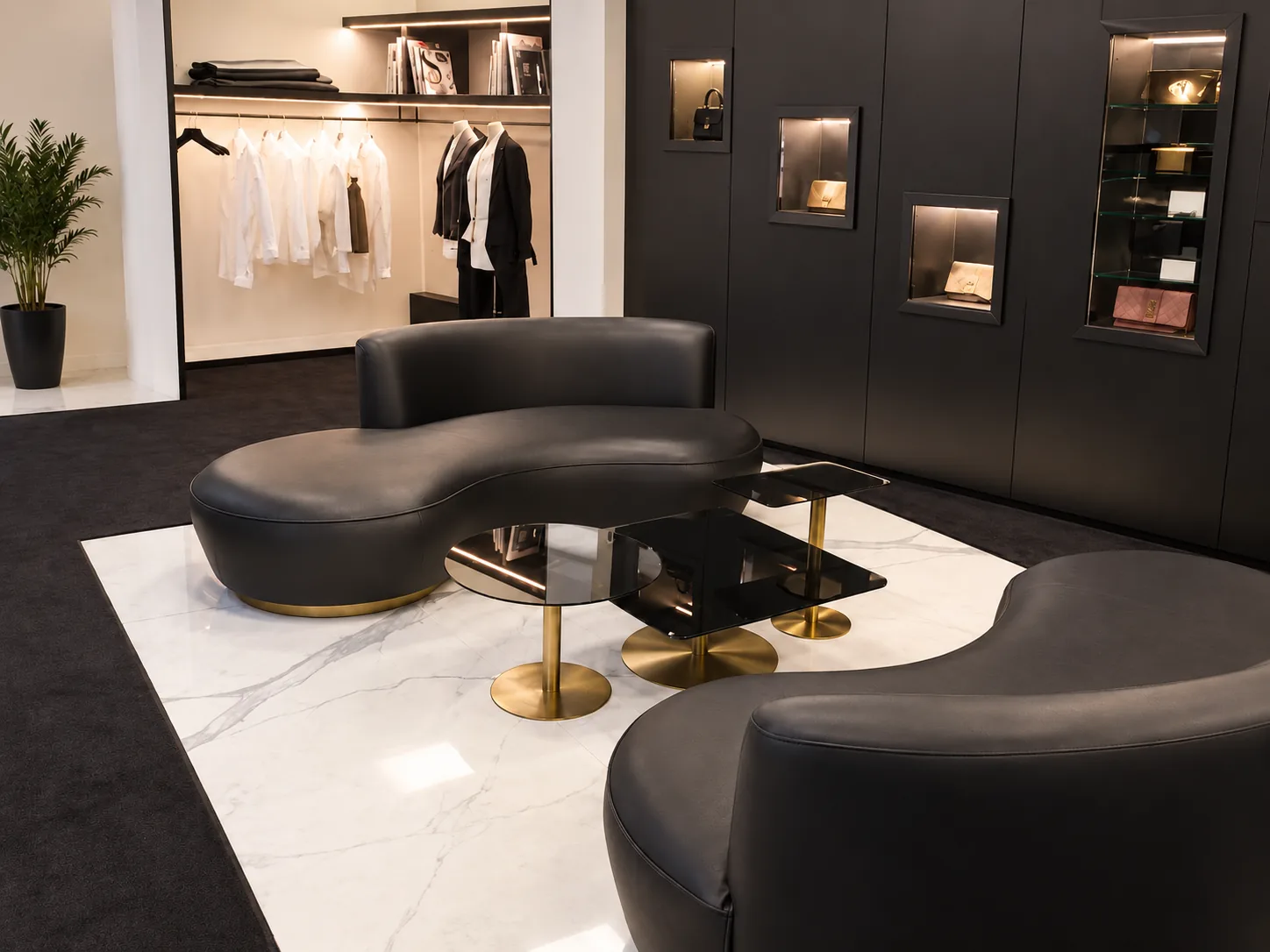 The boutique lounge from the other side: black leather curves around a smoked-glass table