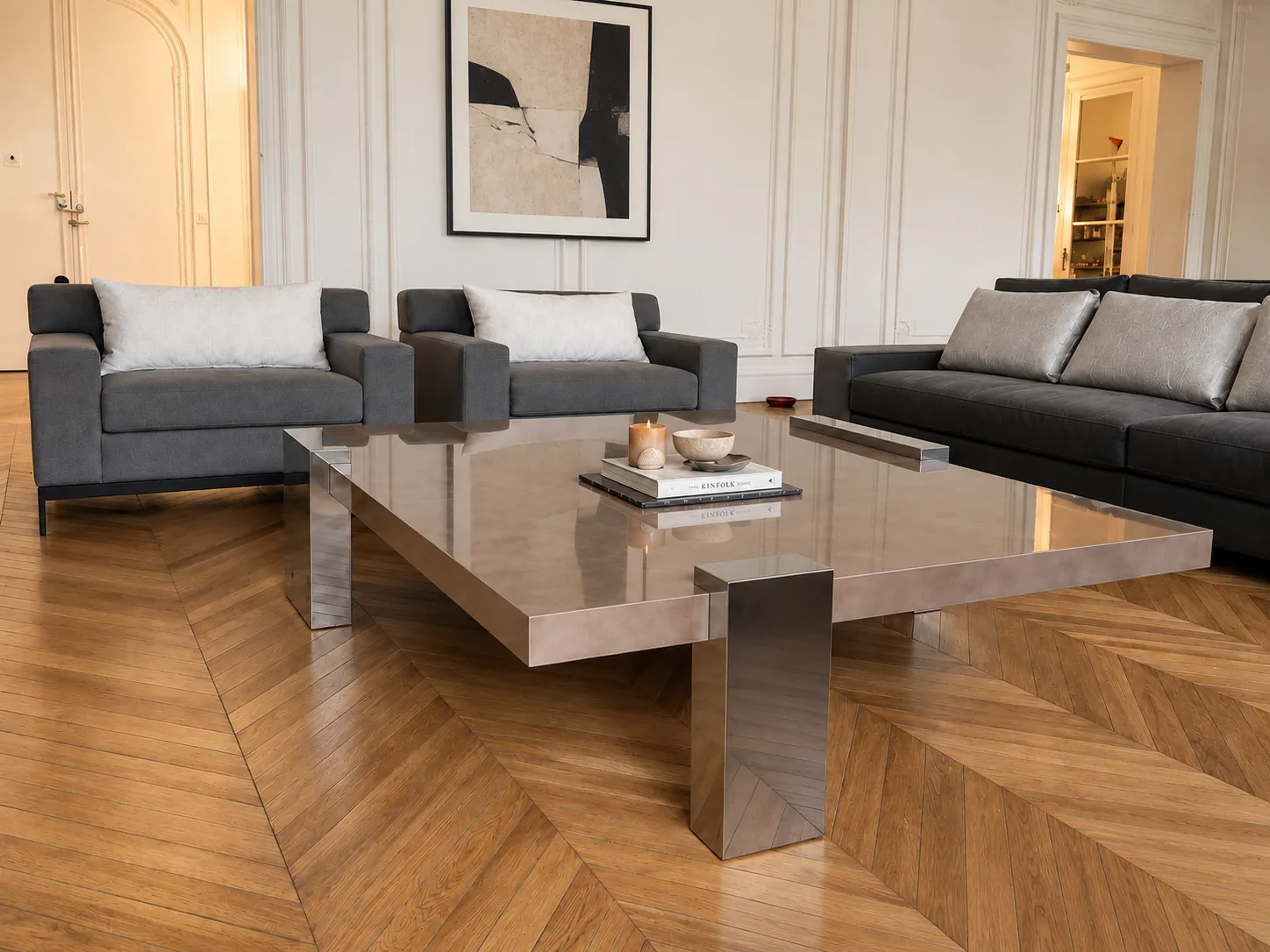 Grey sofas around a large steel and glass coffee table on chevron parquet