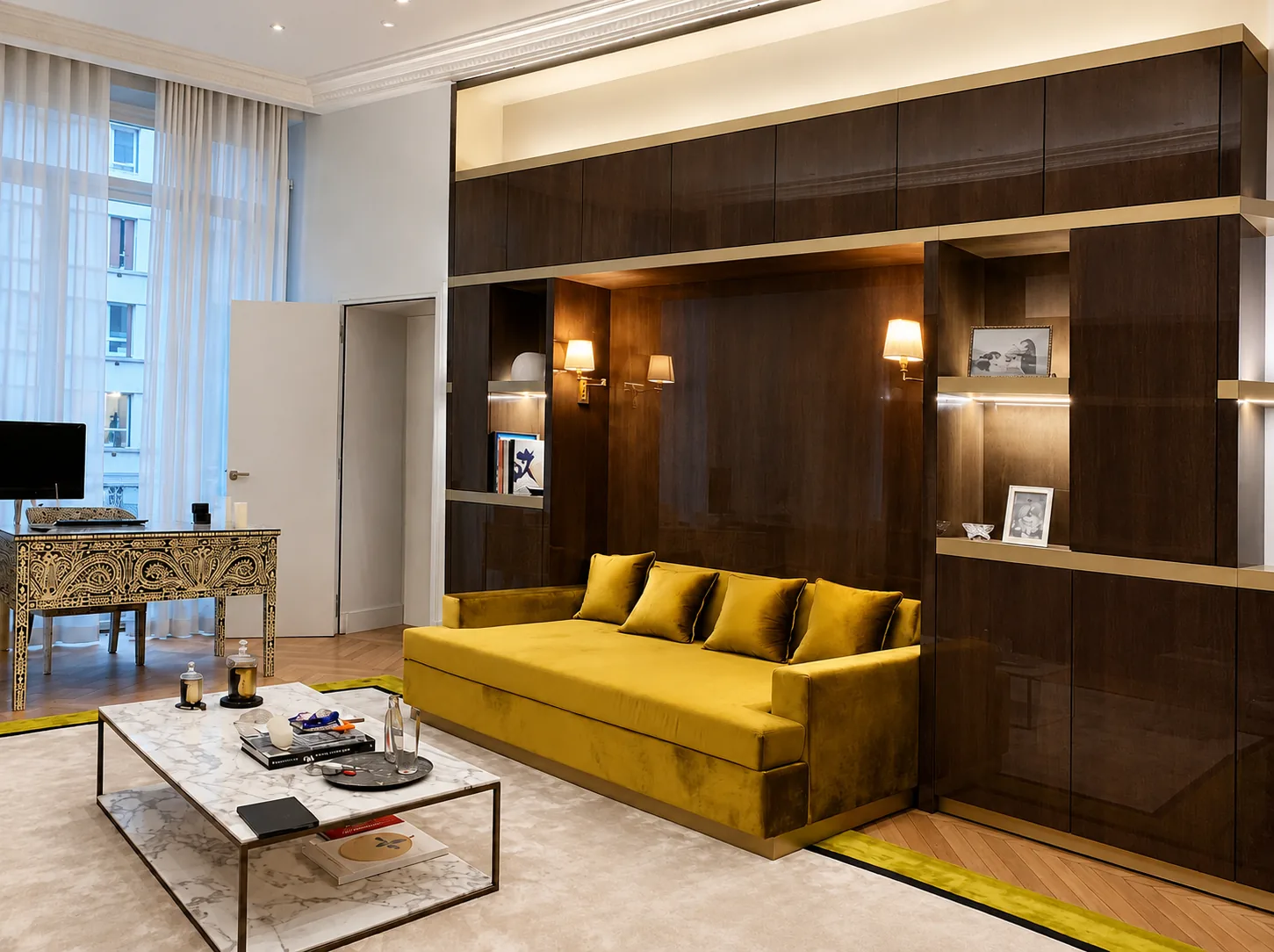 A mustard velvet sofa set into a lit walnut wall unit, with a marble coffee table