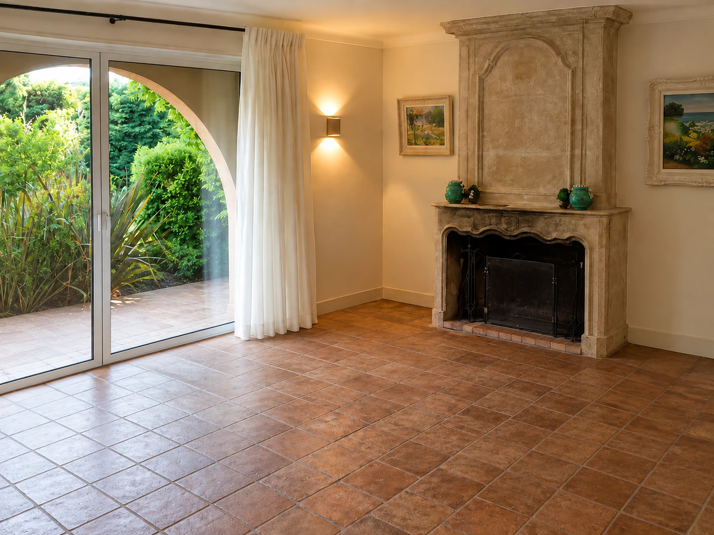 The fireplace side of the room before it was furnished: terracotta tiles, the stone fireplace and the arched garden window