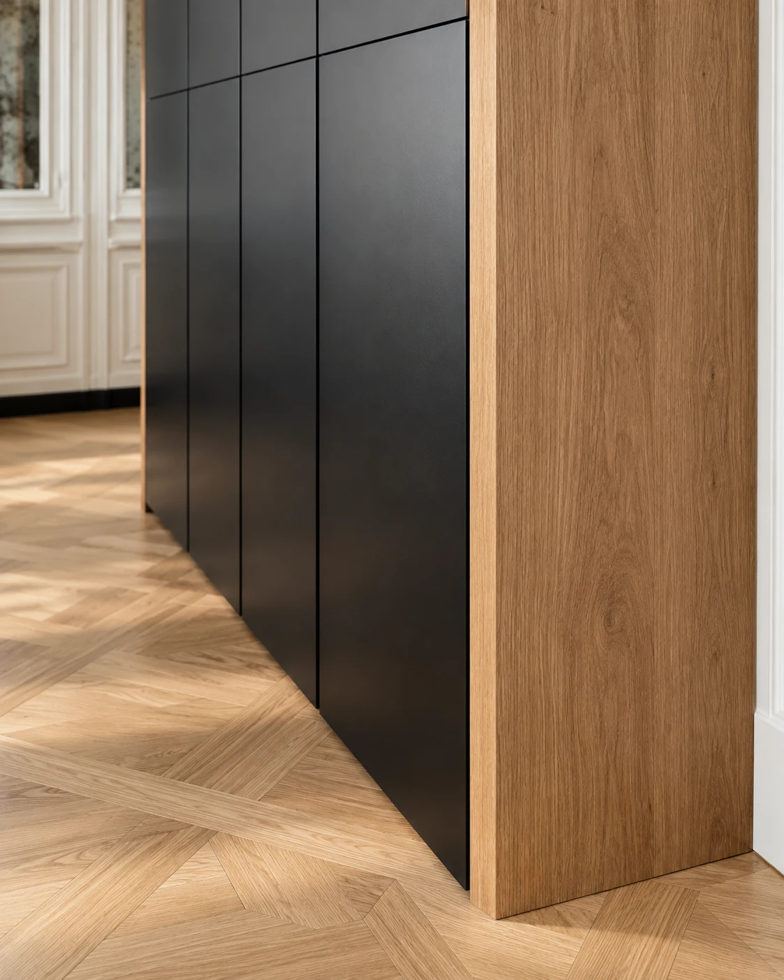 Detail of the cabinet wall: matt black handleless doors framed in oak, on a parquet floor