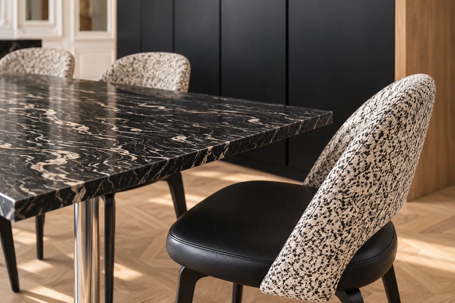 Detail of a dining chair: patterned fabric back, black leather seat, beside the marble table top